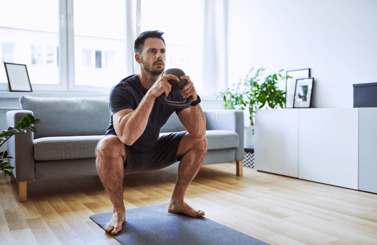A man squats barefoot at home