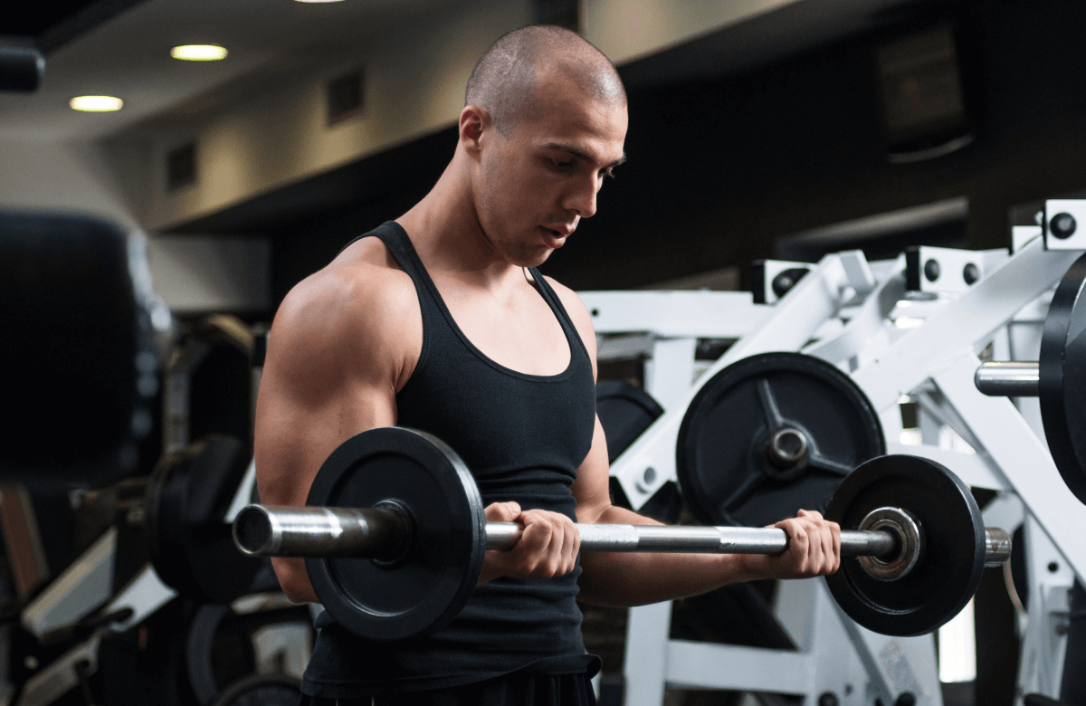 A man does barbell curls as part of a bro split