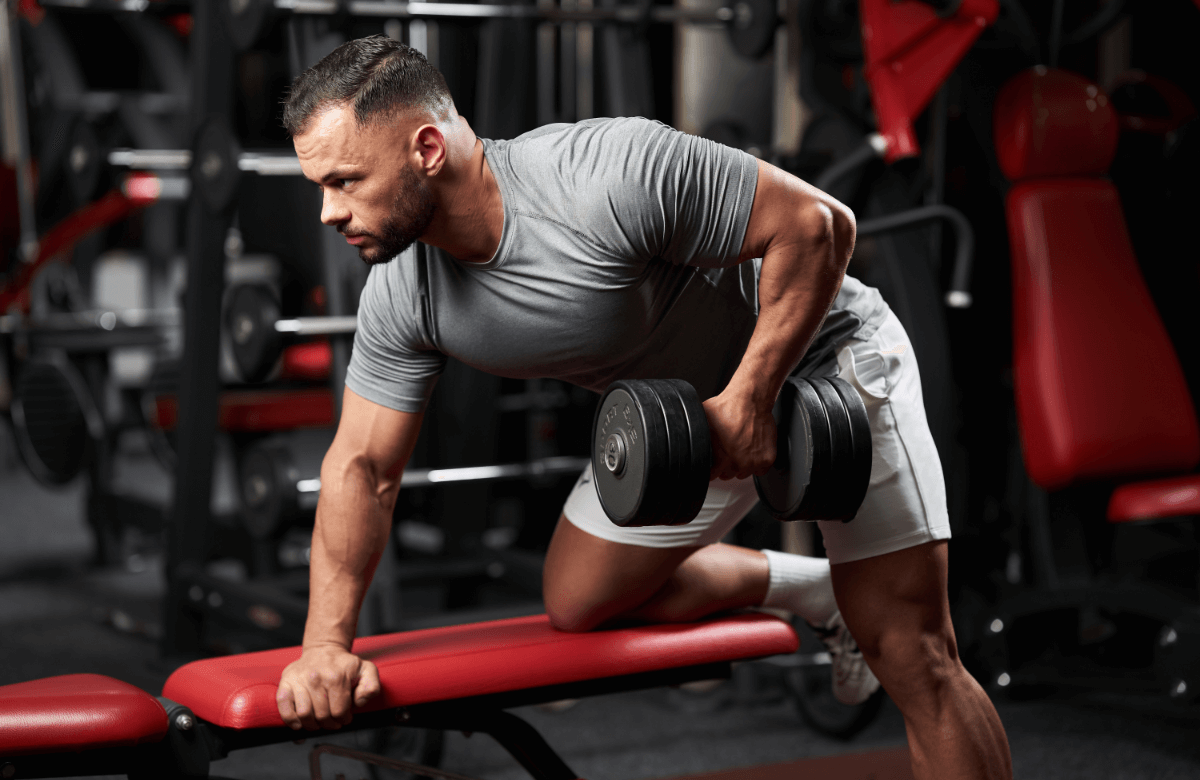 Man does dumbbell rows in a gym