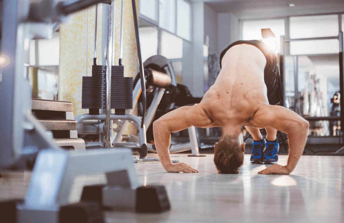 A man does pike push-ups in a gym